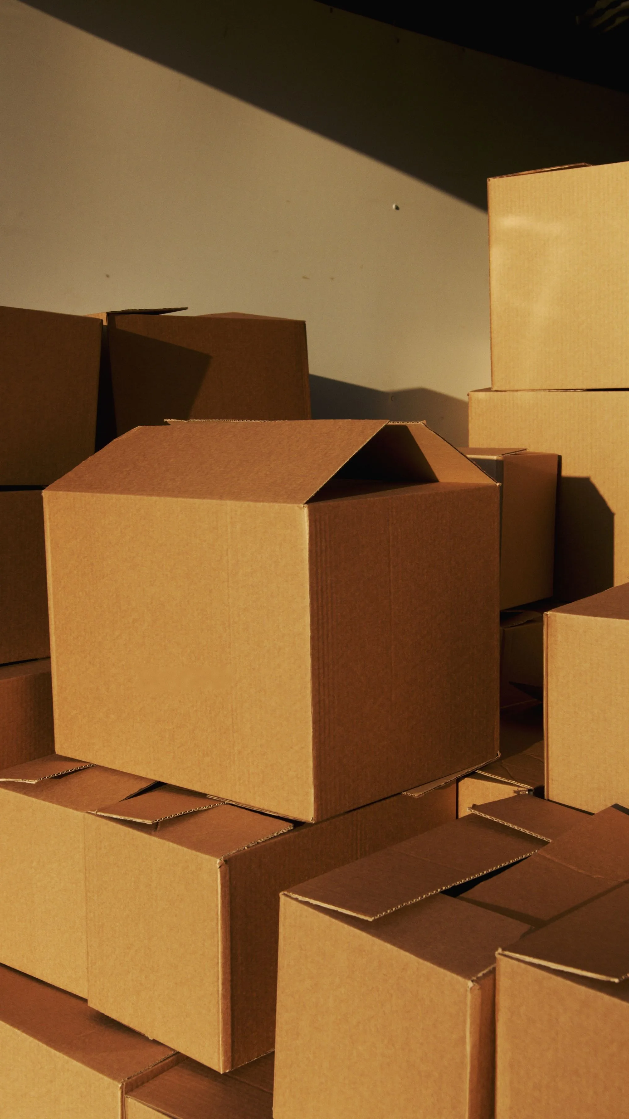 Plain corrugated cartons stacked in warm directional light