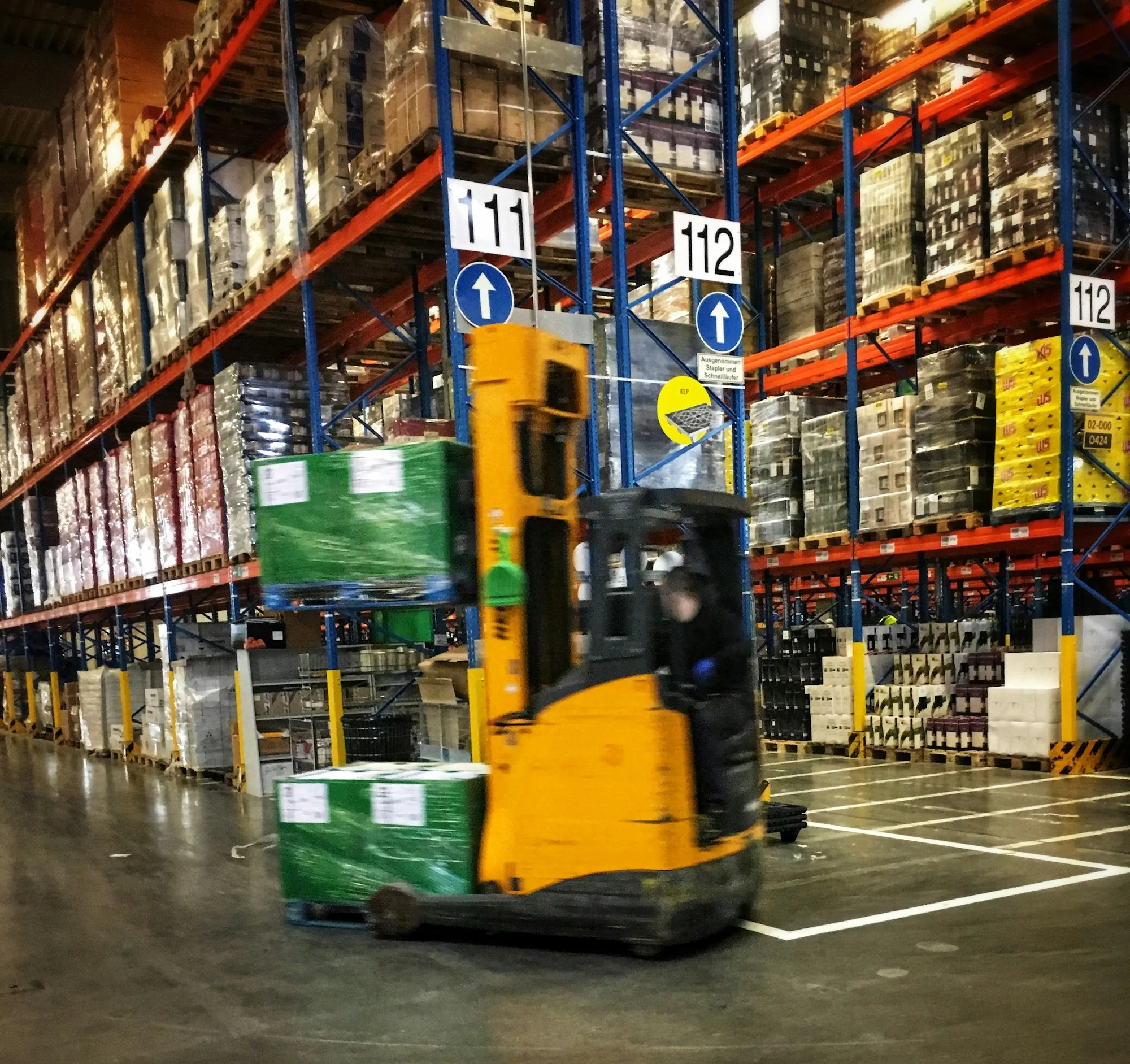 Forklift moving a film-wrapped pallet in a warehouse