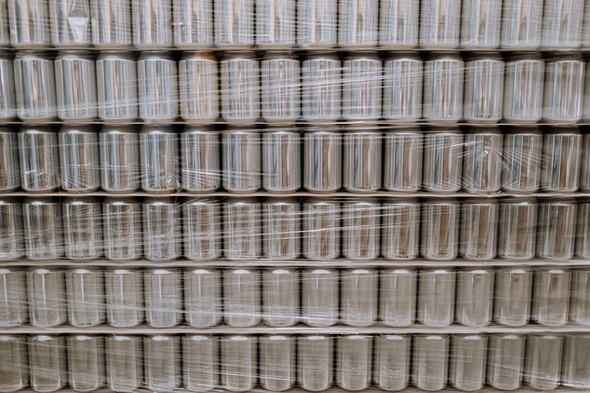 Palletised metal cans secured with transparent stretch film