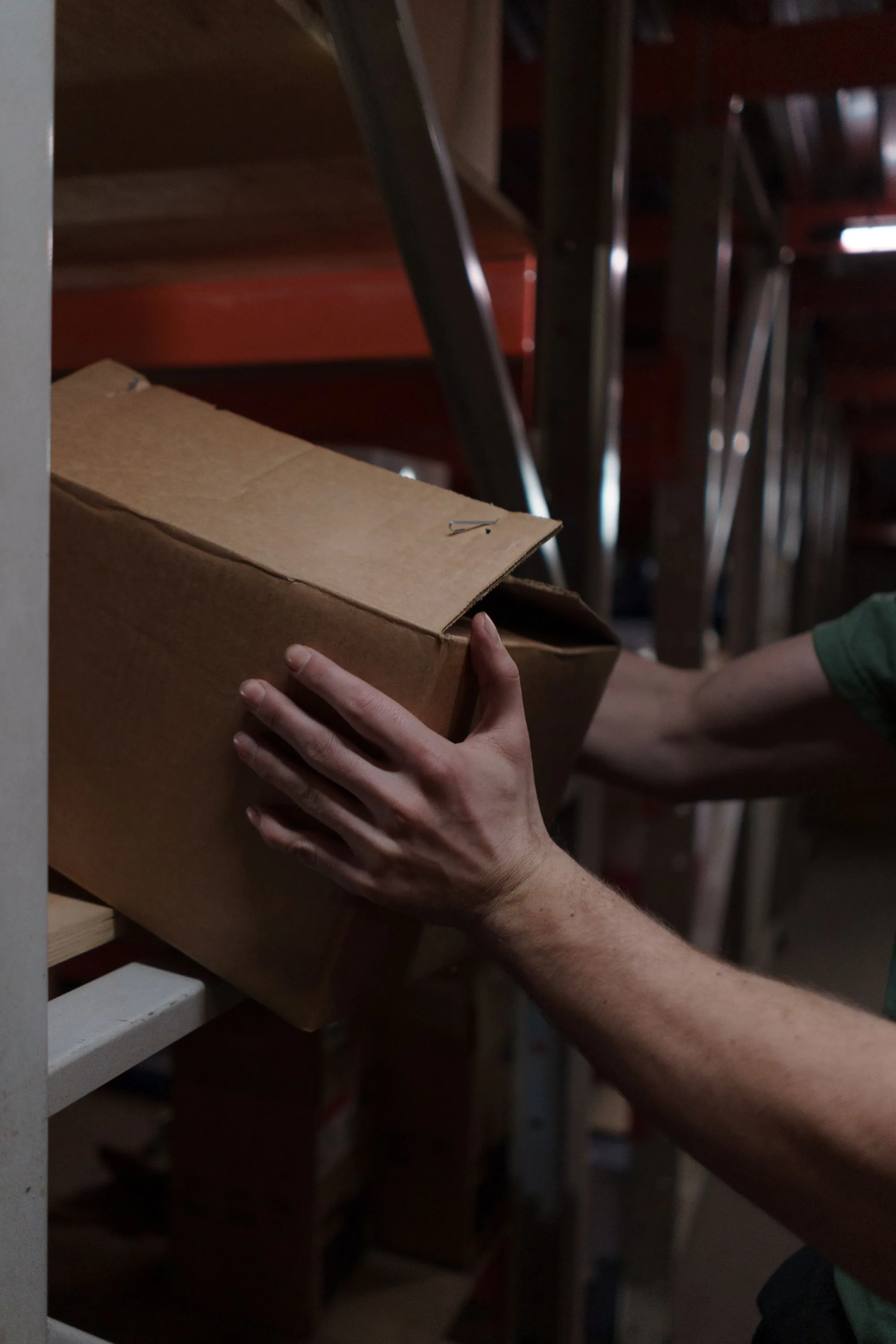 Warehouse worker placing a corrugated carton onto a storage shelf